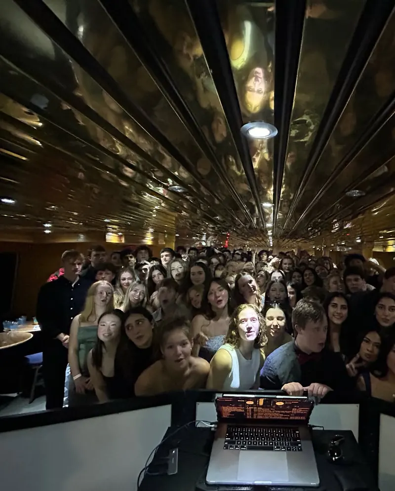 Guests gather around the DJ booth for a photo
