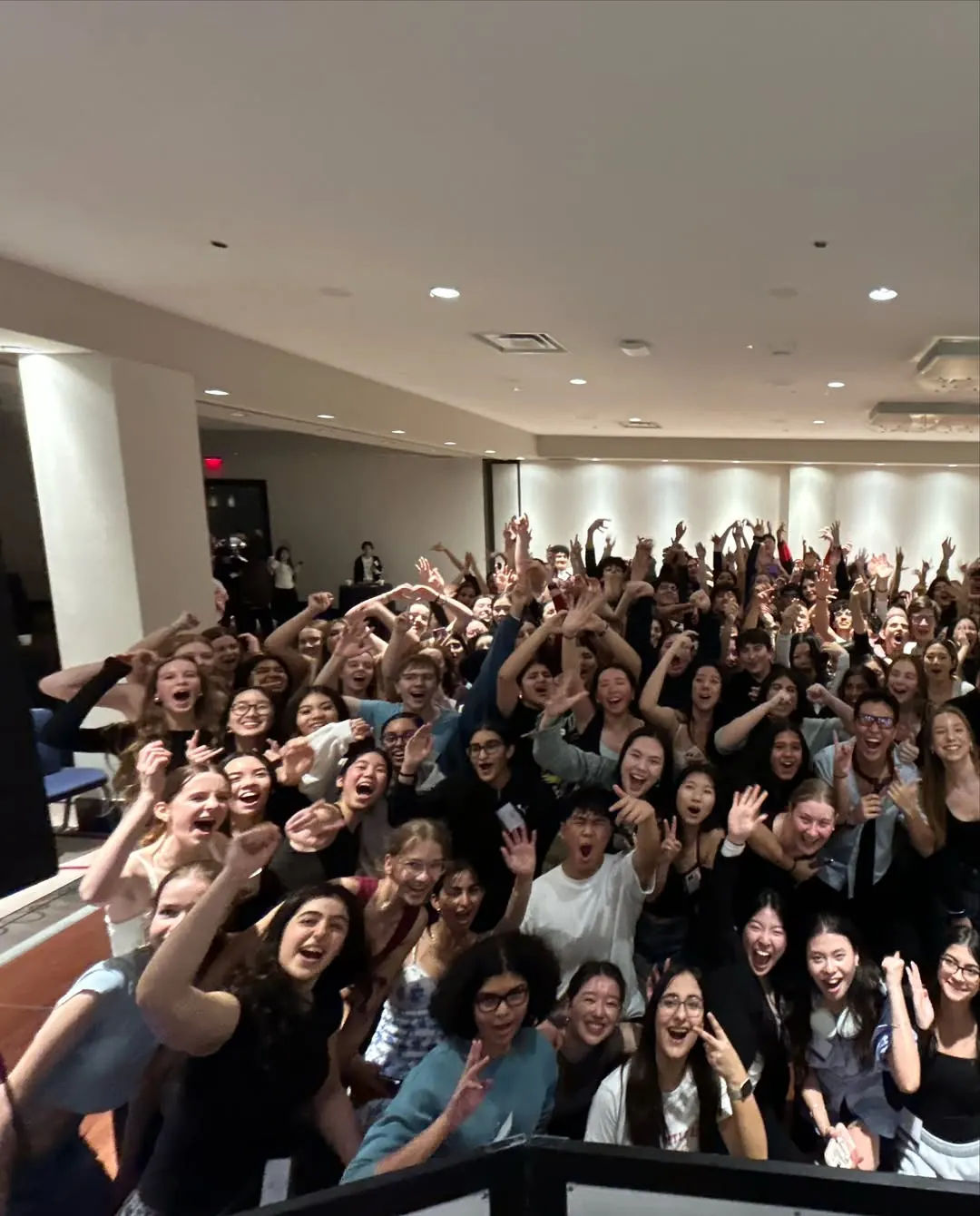 Hundreds of students with their hands up at a school dance