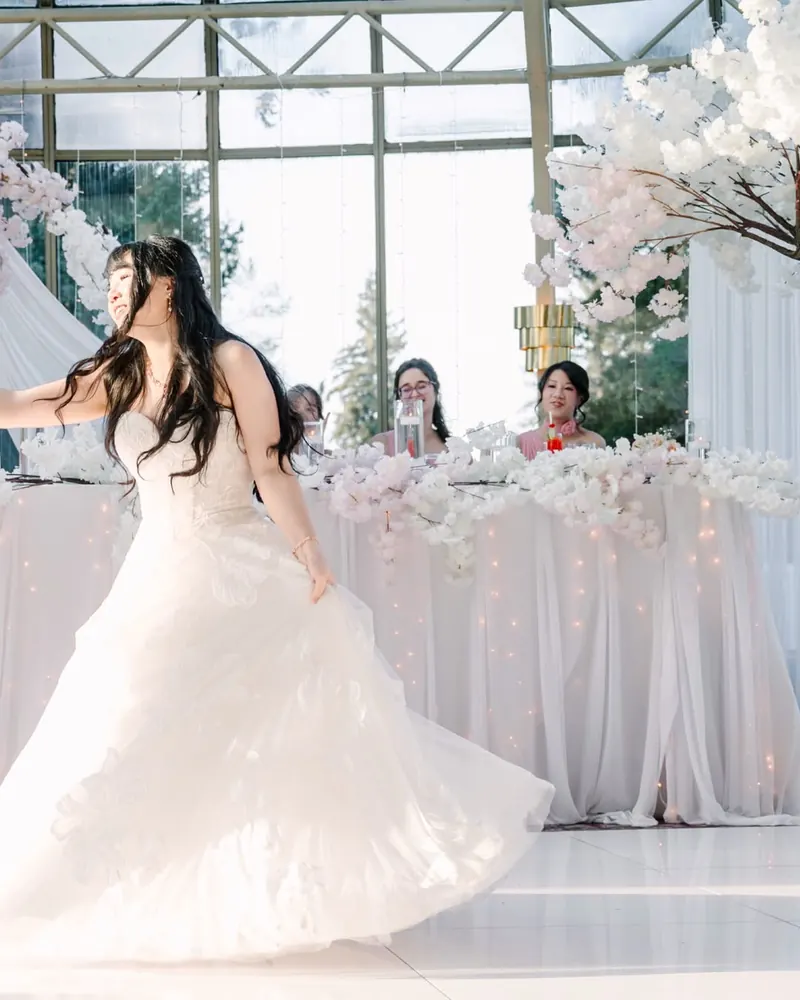 A bride twirls on the dance floor in front of the head table