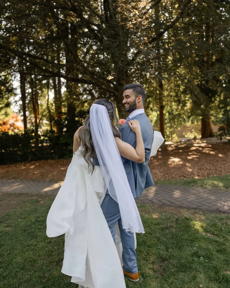 A bride and groom walk among tall trees