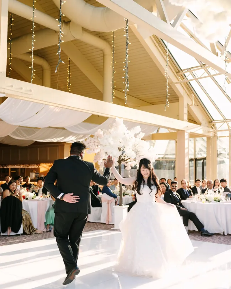 A couple dances under the skylights of a conservatory reception