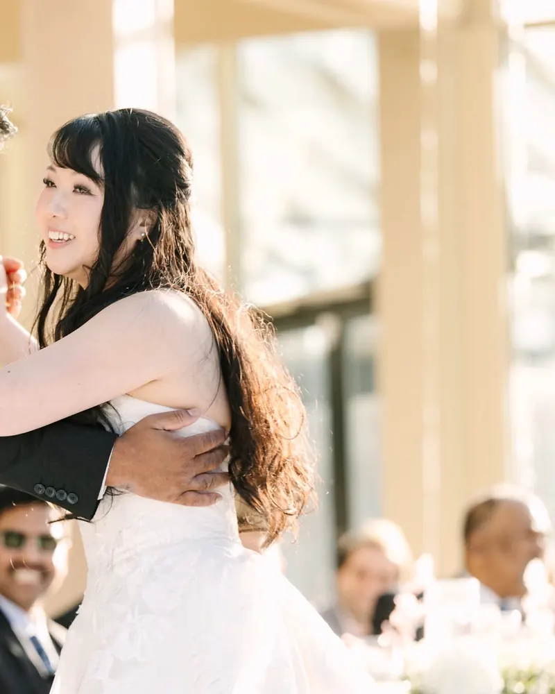 A bride laughs during her first dance as guests look on