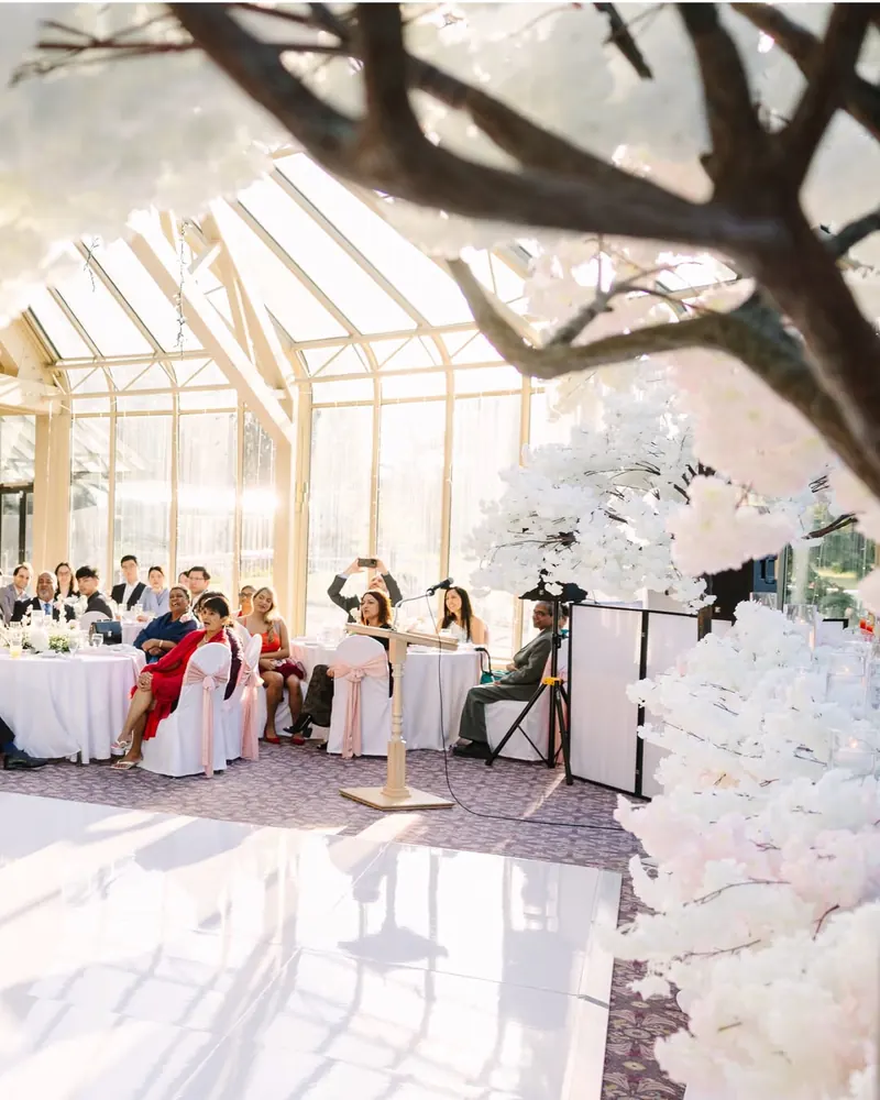 Guests seated around a white dance floor framed by blossom trees