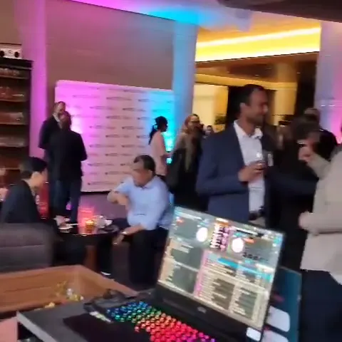 A DJ setup at a corporate reception with pink and blue uplighting