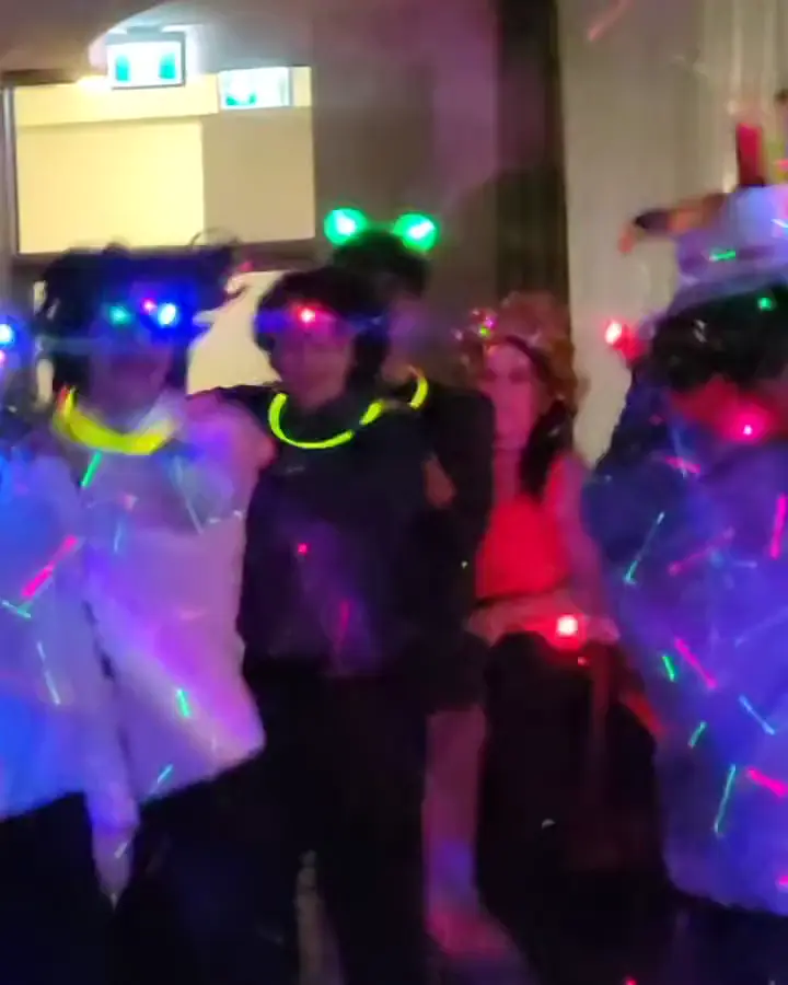 Guests in light-up accessories dancing under lasers