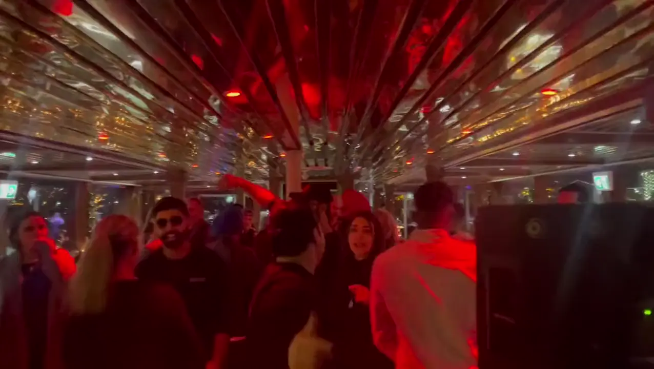 A crowd dancing under a mirrored ceiling washed in red and blue light
